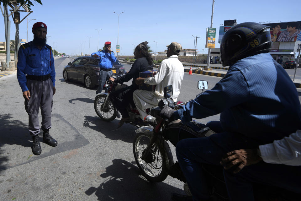 Security personnel brief commuters for alternate route at a barricaded road leading to Clifton beach which closed for public due to approaching cyclone, in Karachi, Pakistan, Monday, June 12, 2023. India and Pakistan braced for the first severe cyclone this year expected to hit their coastal regions later this week, as authorities on Monday halted fishing activities and deployed rescue personnel.(AP Photo/Fareed Khan)