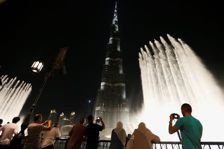 File photo of people watching a fountain in front of Burj Khalifa in Dubai October 9, 2013. REUTERS/Ahmed Jadallah