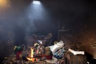 Una mujer y sus hijos intentan calentarse alrededor de una hoguera en su casa de Tilmi.