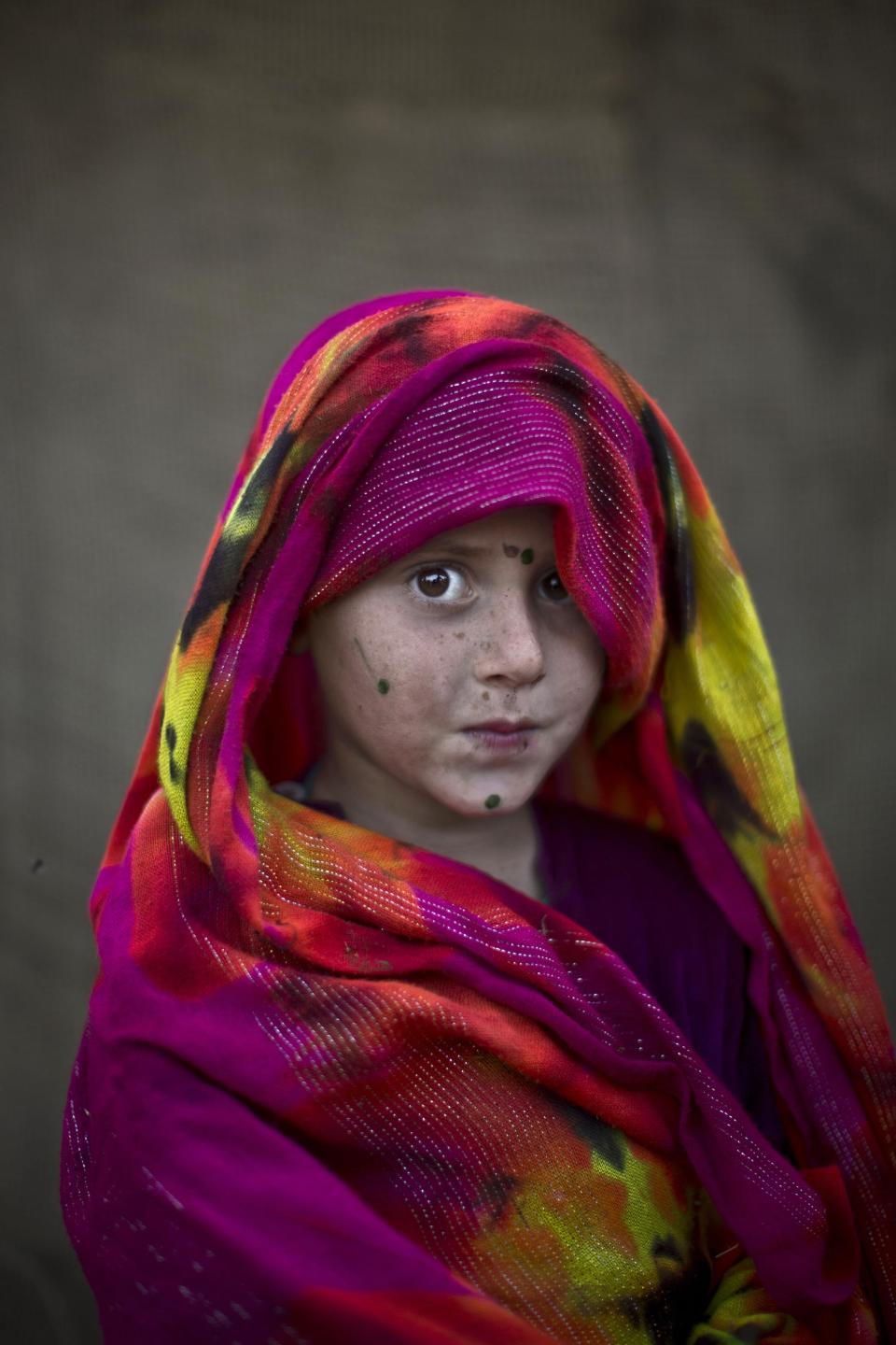 In this Friday, Jan. 24, 2014 photo, Afghan refugee girl, Robina Haseeb, 5, poses for a picture, while playing with other children in a slum on the outskirts of Islamabad, Pakistan. For more than three decades, Pakistan has been home to one of the world’s largest refugee communities: hundreds of thousands of Afghans who have fled the repeated wars and fighting their country has undergone. Since the 2002 U.S.-led invasion of Afghanistan, some 3.8 million Afghans have returned to their home country, according to the U.N.’s refugee agency. (AP Photo/Muhammed Muheisen)
