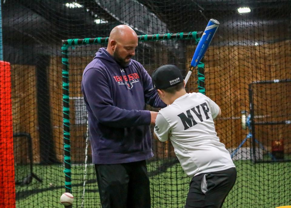 Instructor Jared Evans works with Aidan Potter during a lesson at Inside The Park Batting Cages