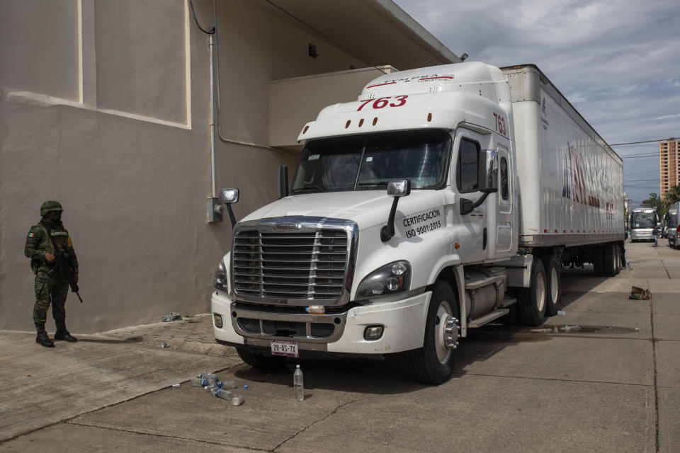 A soldier stands guard by a cargo truck at the Attorney Generals Office after it was intercepted carrying migrants on the highway, in Coatzacoalcos, Veracruz state, Mexico, Friday, Nov. 19, 2021. About 500 migrants were riding in two cargo trucks when they were stopped and detained by the Criminal Investigation Agency and the National Immigration Institute, according to those two organizations. (AP Photo/Felix Marquez)