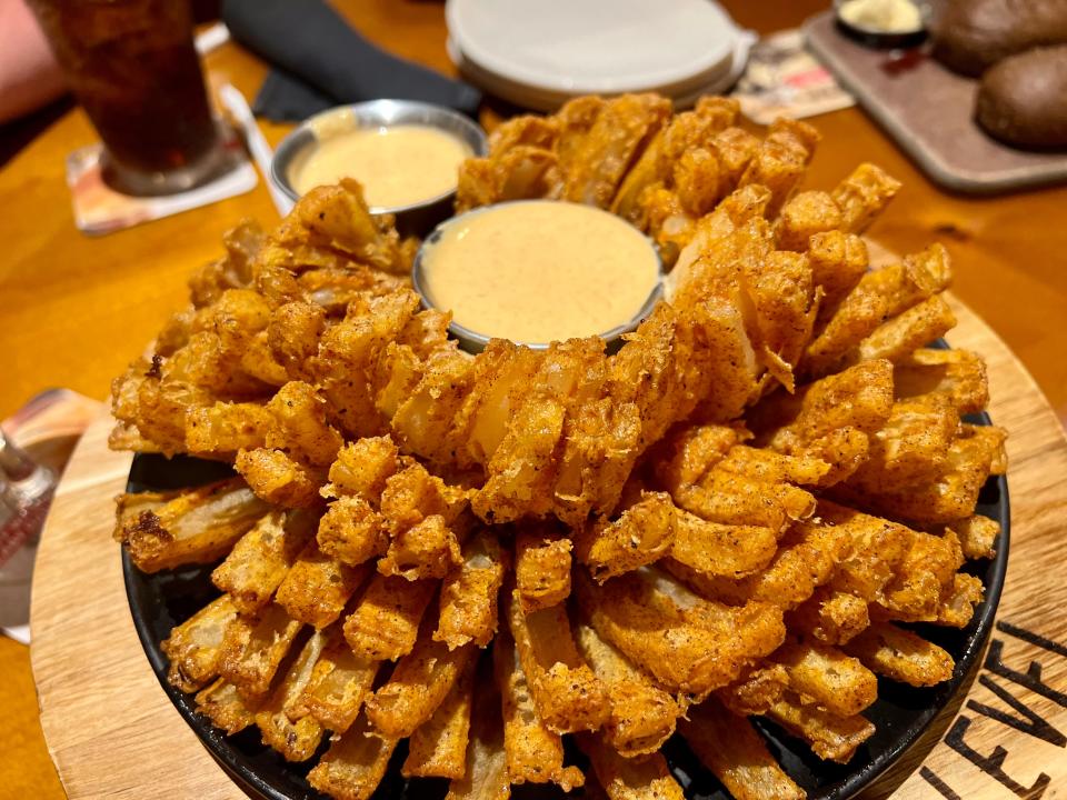 A Bloomin' Onion - a bunch of fried bits of onion stacked on a plate wit hsauce in the middle at Outback Steakhouse