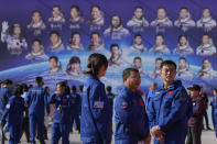 Staff members gather near a billboard depicting Chinese astronauts on the past Shenzhou missions after Chinese astronauts for the upcoming Shenzhou-17 mission met with the press at the Jiuquan Satellite Launch Center in northwest China, Wednesday, Oct. 25, 2023. (AP Photo/Andy Wong)