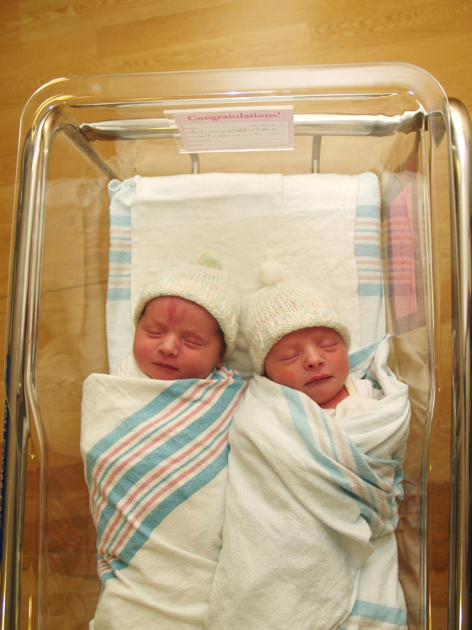 Twins sit in a crib in the hospital
