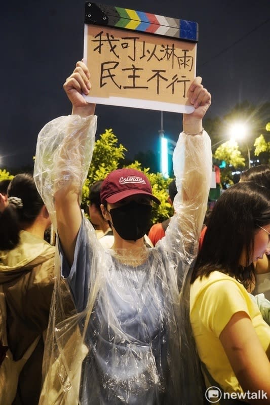  游同學拿著「我可以淋雨，民主不行」的自製手牌站在大雨中和大家一起表達抗議國會惡法的心聲。 圖：張良一攝