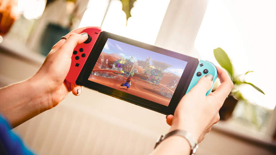  Detail of a young woman playing video games on a Nintendo Switch home console. 