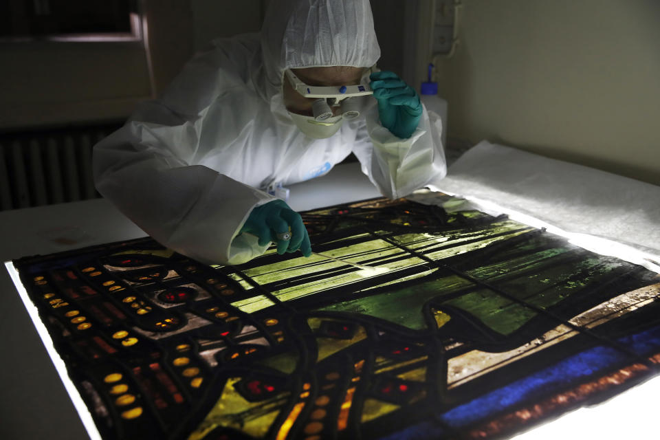 In this photo taken on Wednesday, Oct. 9, 2019, Glass specialist Claudine Loisel checks the Notre Dame cathedral's stained-glass windows in a lab at Champs-sur-Marne, west of Paris. Scientists at the French government's Historical Monuments Research Laboratory are using these objects as clues in an urgent and vital task, working out how to safely restore the beloved Paris cathedral and identify what perils remain inside in a race against the clock. (AP Photo/Francois Mori)