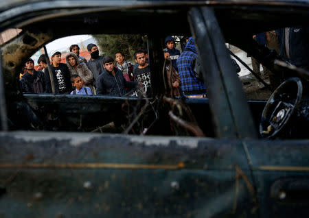 People look at a destroyed vehicle after a suicide bomb attack in Kabul, Afghanistan November 16, 2017. REUTERS/Mohammad Ismail
