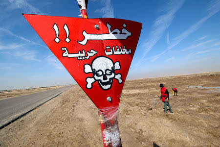 A demining team works close to a danger sign near the village of Bitr, which in Arabic means "amputation", in Shalamjah district, east of Basra, Iraq March 4, 2018. REUTERS/Essam Al-Sudani