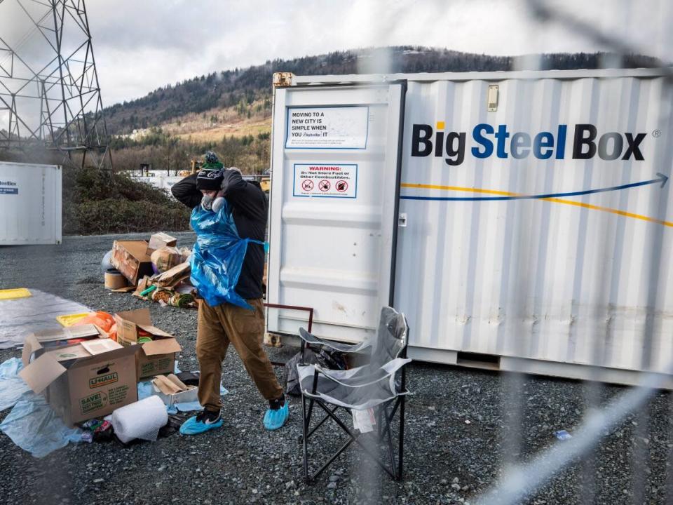 Two people clear out their BigSteelBox storage container that was damaged by floodwaters in Abbotsford, B.C. Customers are criticizing the company for not providing compensation after their storage yard was flooded. (Ben Nelms/CBC - image credit)