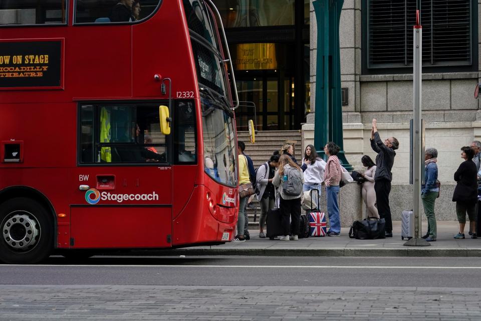 People at a bus stop outside London Liverpool Street (AP)
