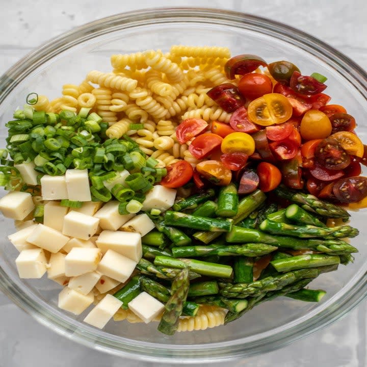 Ingredients for pasta salad in a mixing bowl.