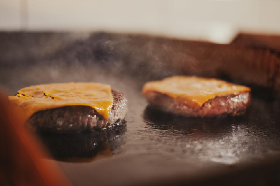 Cheeseburgers frying on the grill.