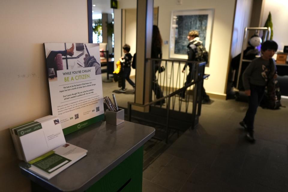 A sign is displayed in the lobby of Limelight Hotel at the base of Snowmass ski mountain Monday, Jan. 9, 2023, in Snowmass, Colo. The kiosk was established for guests to send pre-paid cards to the Senator Joe Manchin, encouraging him to support the climate bill. (AP Photo/Brittany Peterson)