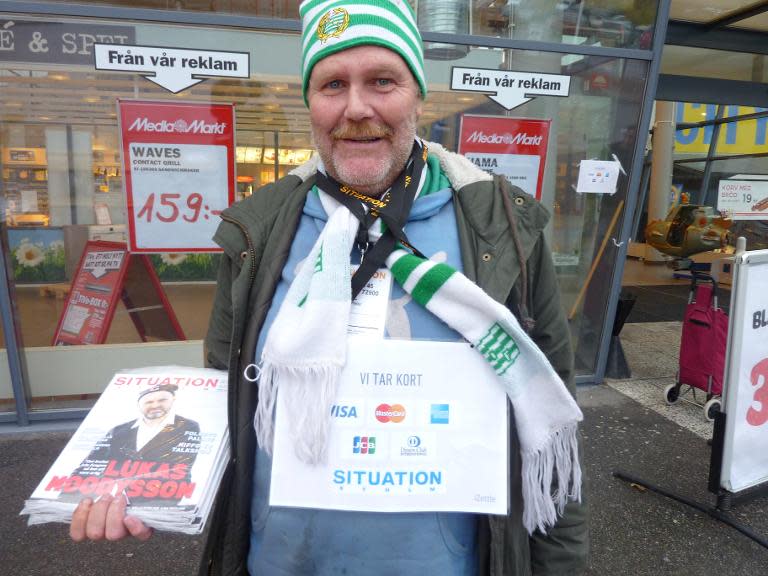 A vendor selling "Situation", a Stockholm paper sold by the homeless to help raise funds, wears a sign reading "we take cards" on October 23, 2013 in Stockholm