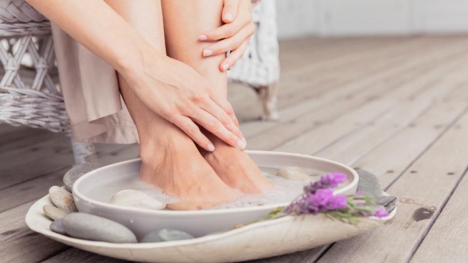 A close-up of a woman soaking her feet in a bowl of warm water 