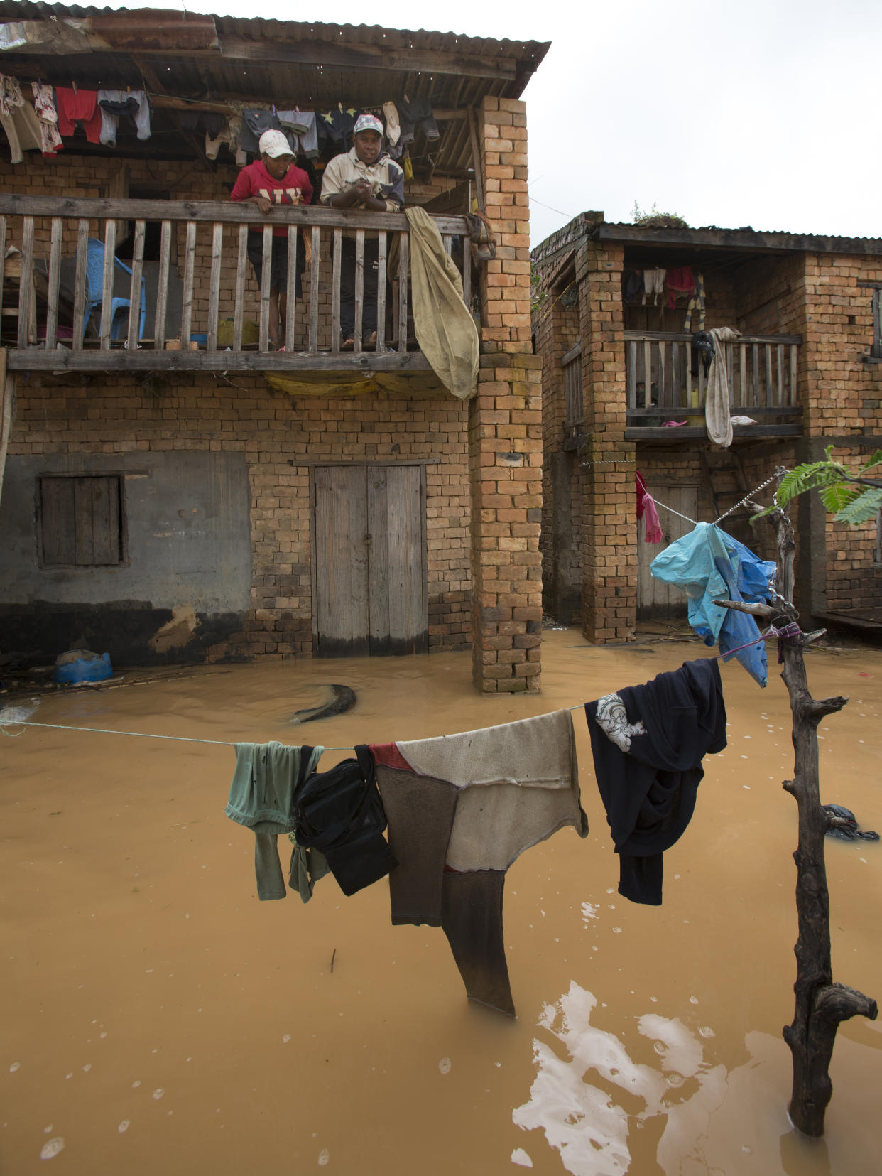 Residents stand on a balcony overlooking a flooded residential street with rain water in Antananarivo, Madagascar, Saturday, Jan. 28, 2023. A tropical storm Cheneso made landfall across north-eastern Madagascar on January 19, brought strong winds to coastal regions, while heavy rain brought significant flooding to northern parts of the country. (AP Photo/Alexander Joe)