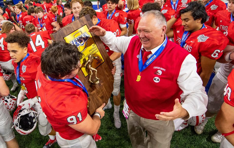 Center Grove High School head coach Eric Moore and senior Caden Curry (91) celebrate with the trophy after an IHSAA class 6A State Championship football game against Westfield High School, Saturday, Nov. 27, 2021, at Lucas Oil Stadium. Center Grove won 27-21.