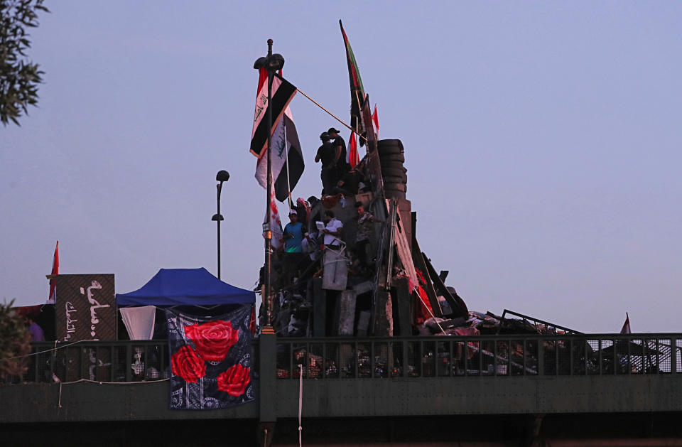 Anti-government protesters stand on barriers set up by Iraqi security forces to close a bridge leading to the Green Zone government areas during ongoing protests in Baghdad, Iraq, Tuesday, Nov. 5, 2019. (AP Photo/Hadi Mizban)