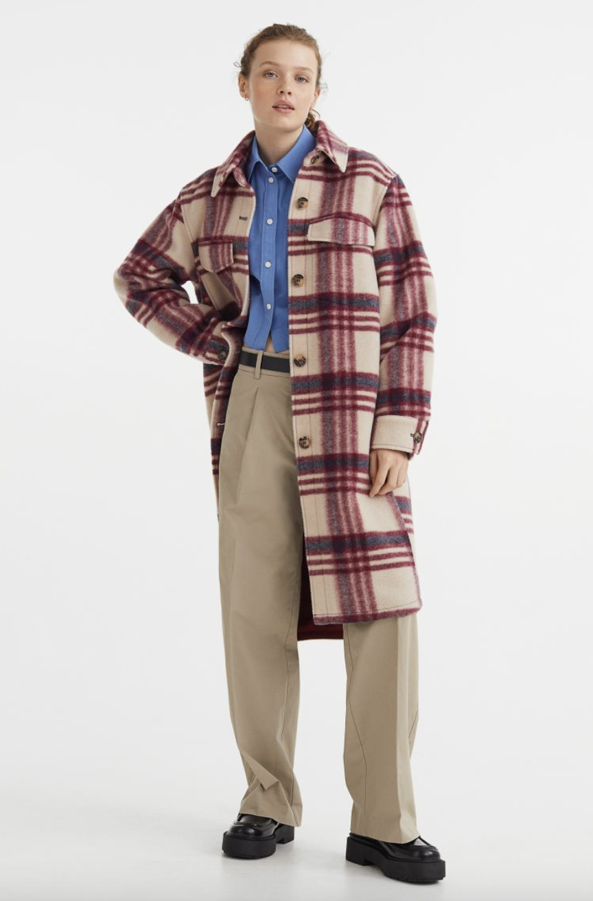 model wearing beige pants, blue shirt, and pink and beige plaid Long Shacket (Photo via H&M)