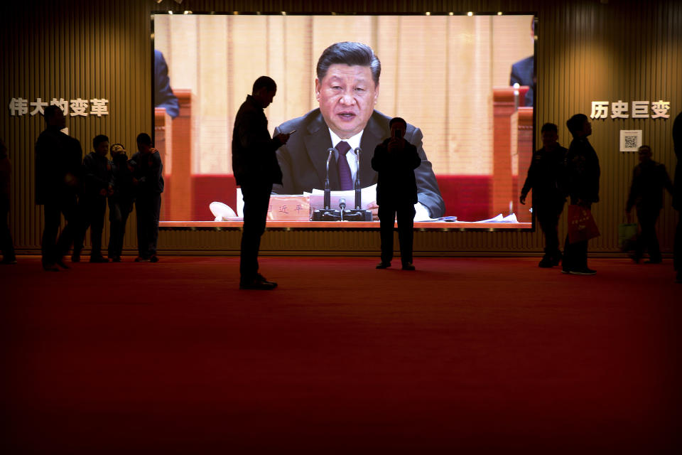 People walk past a video screen displaying an image of Chinese President Xi Jinping at an exhibition commemorating the 40th anniversary of China's Reform and Opening Up Movement at the National Museum in Beijing, Friday, March 1, 2019. Thousands of delegates from around China are gathering in Beijing for next week's annual session of the country's rubber-stamp legislature and its advisory body. (AP Photo/Mark Schiefelbein)