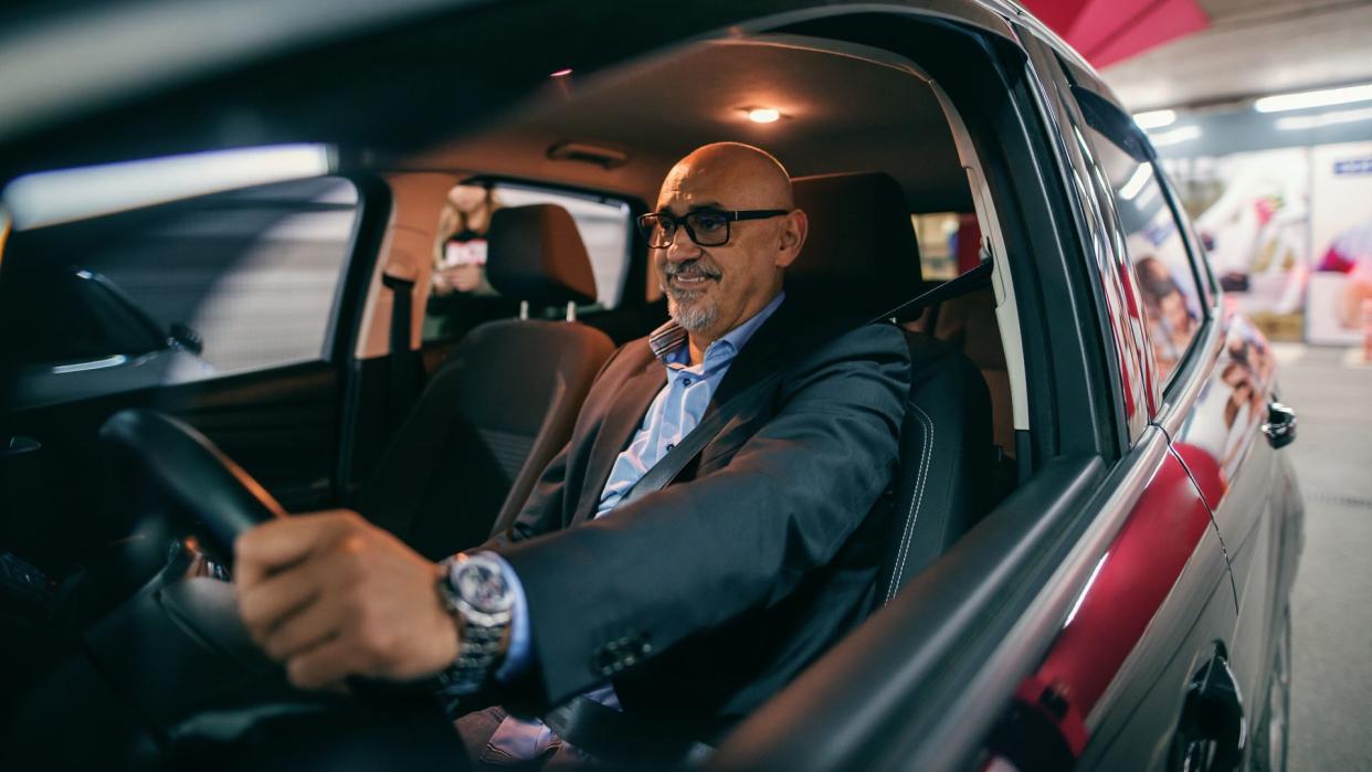 Smiling bearded senior adult driving car at night.