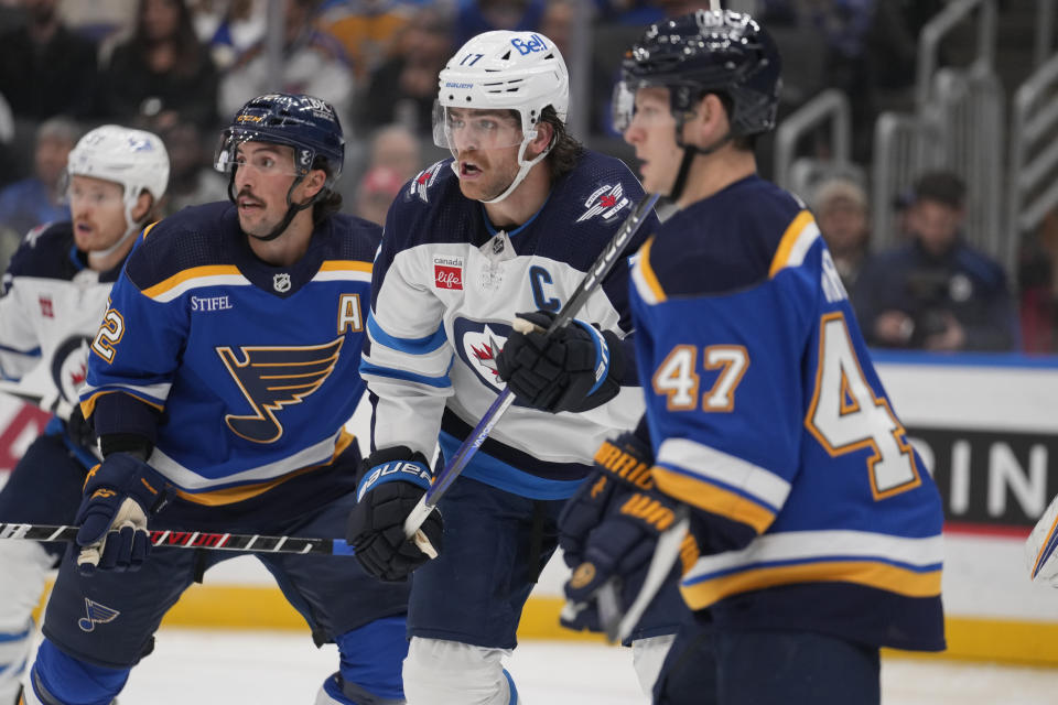 Winnipeg Jets' Adam Lowry, center, skates between St. Louis Blues' Justin Faulk, left, and Torey Krug (47) during the first period of an NHL hockey game Tuesday, Nov. 7, 2023, in St. Louis. (AP Photo/Jeff Roberson)