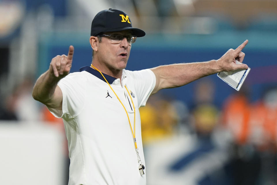FILE - Michigan coach Jim Harbaugh gestures during warmups before the team's Orange Bowl NCAA college football playoff semifinal against Georgia, Dec. 31, 2021, in Miami Gardens, Fla. Harbaugh will be the coach of the Los Angeles Chargers, leaving Michigan after capping his ninth season as coach of college football’s winningest program with the school’s first national championship since 1997, two people familiar with the situation told The Associated Press. The people spoke to the AP on condition of anonymity because the team hasn’t made the announcement. (AP Photo/Lynne Sladky, File)
