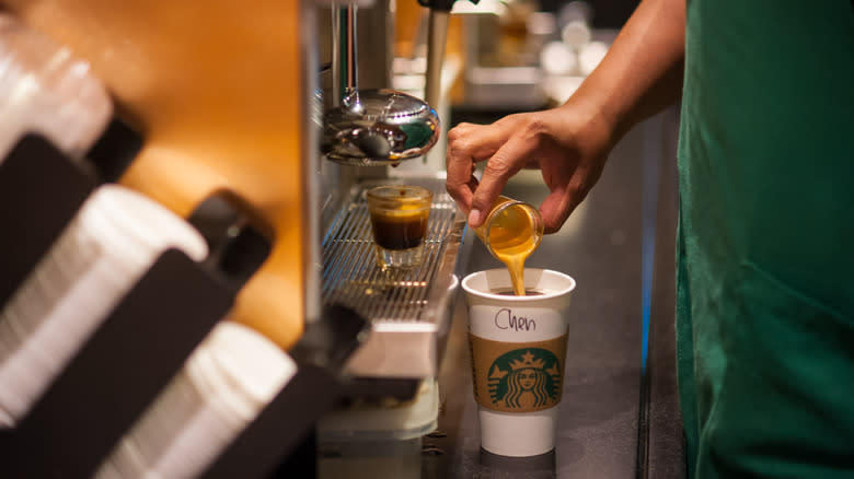 Barista pouring espresso shot into cup 