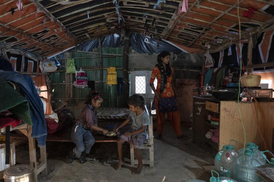 Arima, 7, left, eats breakfast with her brother Kartik, 4, as their mother Meera Devi looks on inside their shanti on the flood plain of Yamuna River, in New Delhi, India, Friday, Sept. 29, 2023. Their family were among the hundreds that were displaced by the recent floods in the Indian capital's Yamuna River. (AP Photo/Altaf Qadri)