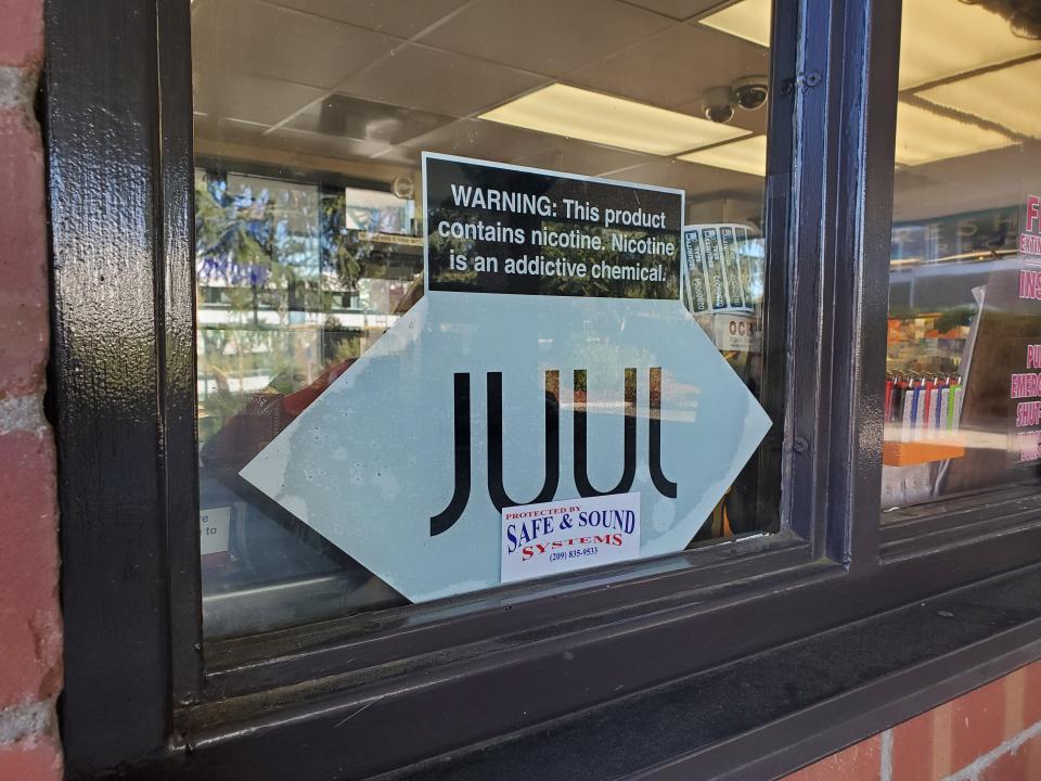 Close-up of logo for e-cigarette or vape company Juul on glass window of convenience store