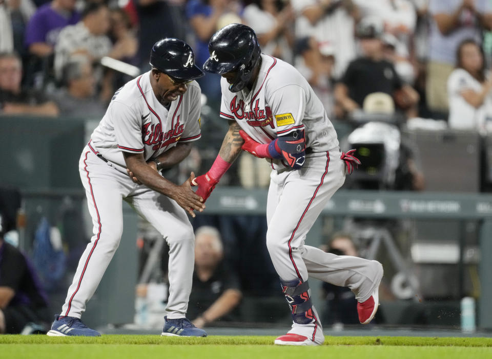 Atlanta Braves third base coach Ron Washington, left, congratulates Orlando Arcia as he circles the bases after hitting a two-run home run against Colorado Rockies starting pitcher Kyle Freeland in the sixth inning of a baseball game Wednesday, Aug. 30, 2023, in Denver. (AP Photo/David Zalubowski)