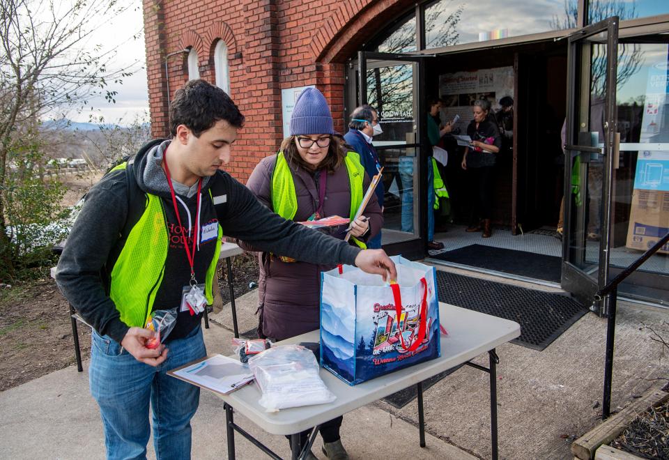 Nicholas Poulos, left, and Chloe Donohoe, grab packs of hand warmers and feminine products for unhoused individuals before volunteering for the annual point in time count in Asheville, January 30, 2024.
