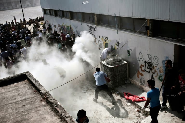 Kos policemen try to disperse hundreds of migrants by spraying them with fire extinguishers during a gathering for a registration procedure on August 11, 2015