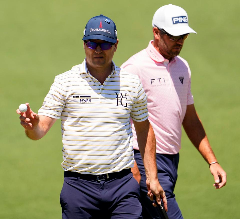 Apr 12, 2024; Augusta, Georgia, USA; Zach Johnson holds up his ball after making a putt on no. 2 as Corey Conners walks by on the green during the second round of the Masters Tournament. Mandatory Credit: Rob Schumacher-USA TODAY Network