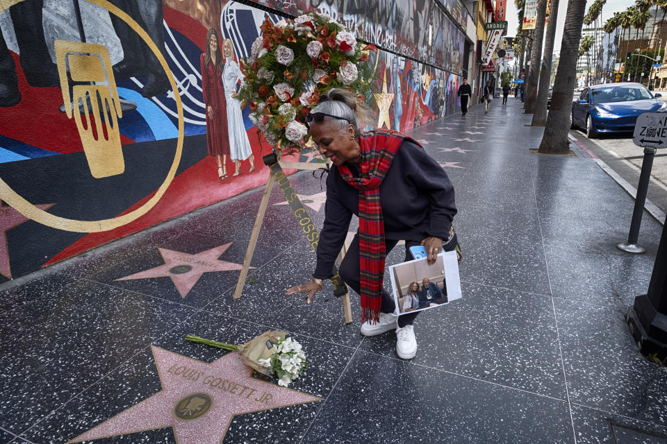 Miriam Holder Jacobs, a former personal assistant to Louis Gossett Jr., pays her respects at a memorial wreath on the Hollywood Walk of Fame for the star in the Hollywood section of Los Angeles on Friday, March 29,2024. Gossett was the first Black man to win a supporting actor Oscar and an Emmy winner for his role in the seminal TV miniseries "Roots," has died. He was 87. (AP Photo/Richard Vogel)