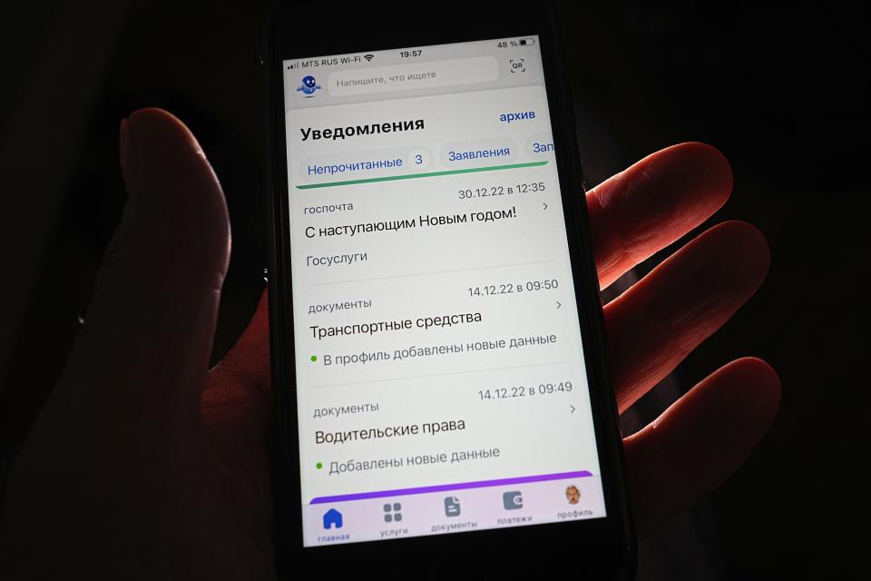 A person poses with a smartphone screen showing an open page of Gosuslugi website, in Moscow, Russia, Tuesday, April 11, 2023. Russian lawmakers have approved legislation that would allow authorities to issue electronic summons to draftees and reservists. The State Duma voted to pass the bill Tuesday on its second and third readings and still needs approval from the upper house of parliament and President Vladimir Putin’s signature to take effect. (AP Photo)