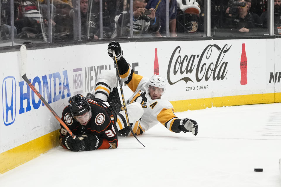 Anaheim Ducks' Derek Grant (38) and Pittsburgh Penguins' Brian Dumoulin (8) crash into the boards while chasing the puck during the third period of an NHL hockey game Friday, Feb. 10, 2023, in Anaheim, Calif. The Penguins won 6-3. (AP Photo/Jae C. Hong)