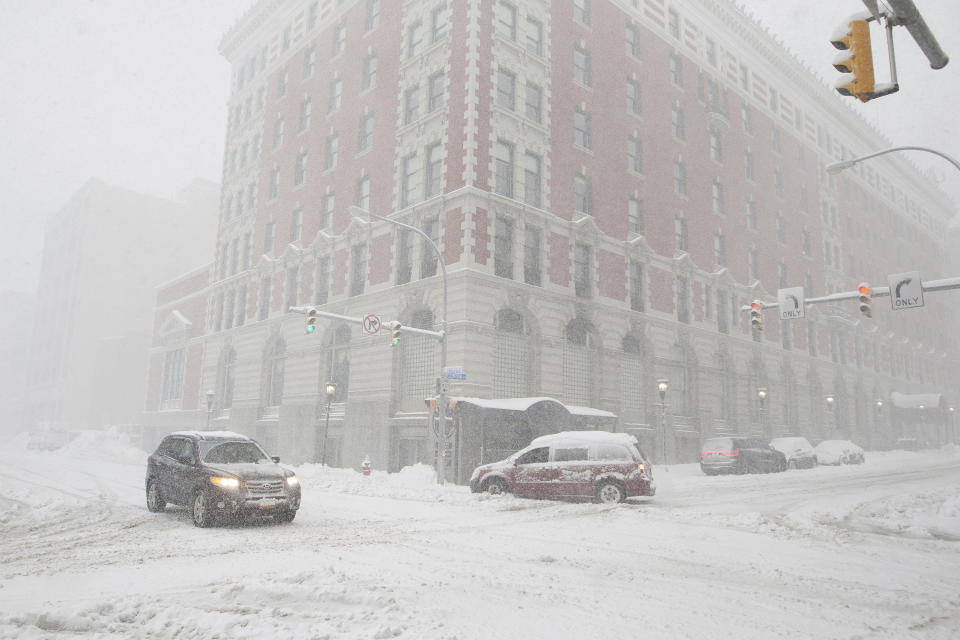 Cars drive along Ellicott Street as snow falls Friday, Nov. 18, 2022, in Buffalo, N.Y. A dangerous lake-effect snowstorm paralyzed parts of western and northern New York, with nearly 2 feet of snow already on the ground in some places and possibly much more on the way. (AP Photo/Joshua Bessex)