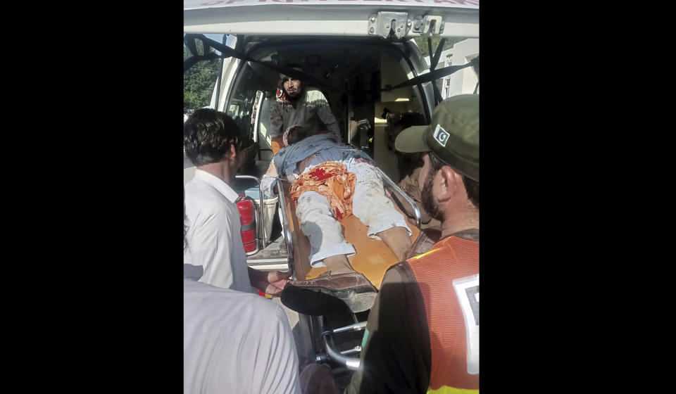 In this photo provided by Rescue 1122 Head Quarters, rescue workers carry a wounded man after a bomb explosion in the Bajur district of Khyber Pakhtunkhwa, Pakistan, Sunday, July 30, 2023. A powerful bomb ripped through a rally by supporters of a hard-line cleric and political leader in the country’s northwestern Bajur district that borders Afghanistan on Sunday, killing at least 10 people and wounding more, police said. (Rescue 1122 Head Quarters via AP)