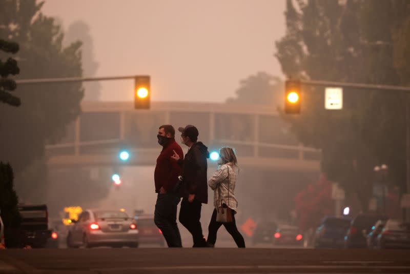 Local residents cross a street as smoke from wildfires covers an area near Salem, Oregon