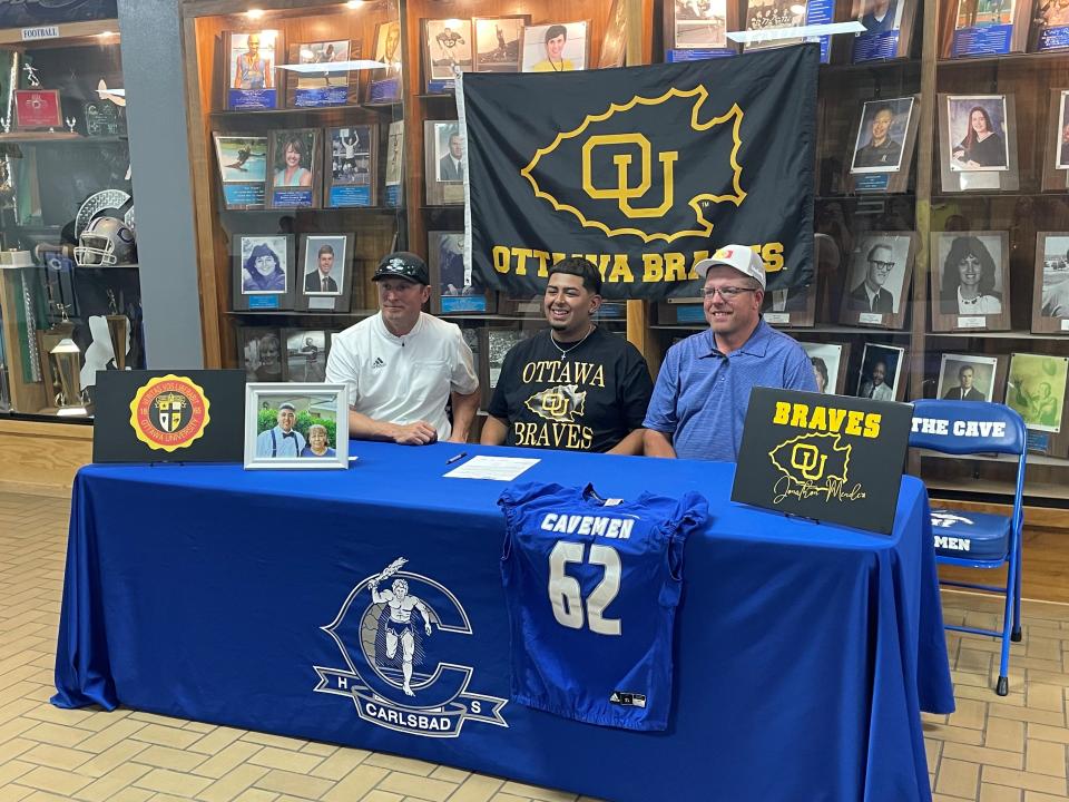 From left to right: Carlsbad High School head football coach Cale Sanders, Jonathan Mendez and coach Bryan Jones during a national letter of intent signing on May 10, 2023 at Carlsbad High School.