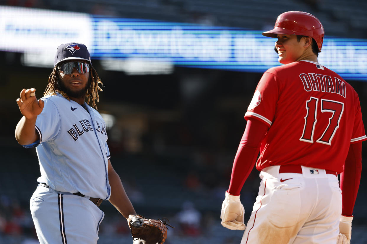 ANAHEIM, CALIFORNIA - AUGUST 10: Shohei Ohtani #17 of the Los Angeles Angels and Vladimir Guerrero Jr. #27 of the Toronto Blue Jays react while on first base during the sixth inning of game one of a doubleheader at Angel Stadium of Anaheim on August 10, 2021 in Anaheim, California. (Photo by Michael Owens/Getty Images)