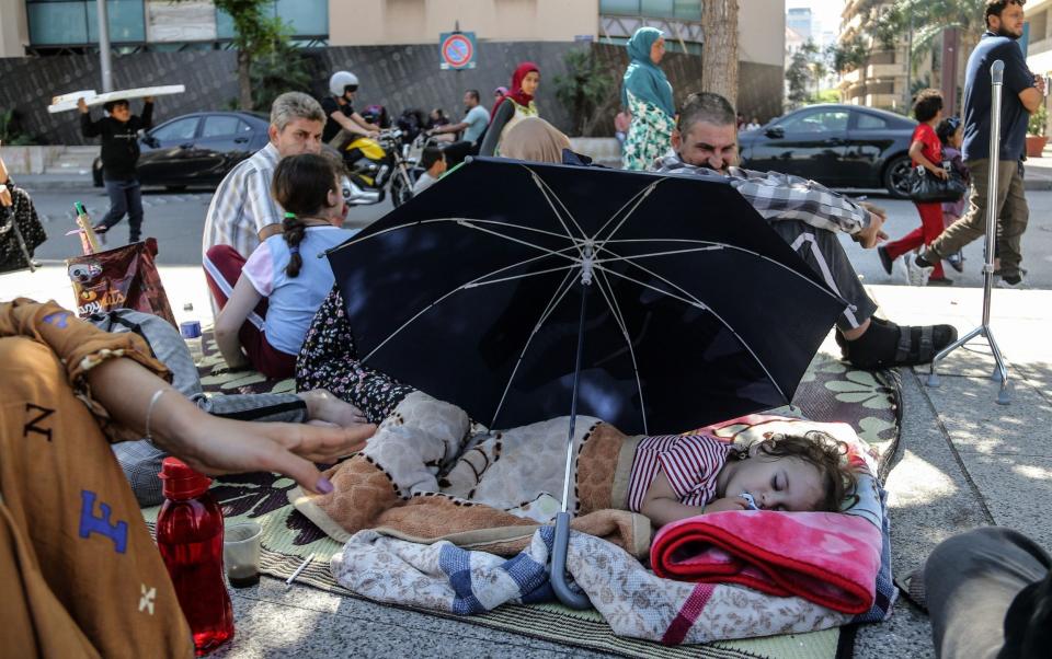 A young girl sleeps under an umbrella among the families forced on to the streets by the Israeli bombardment