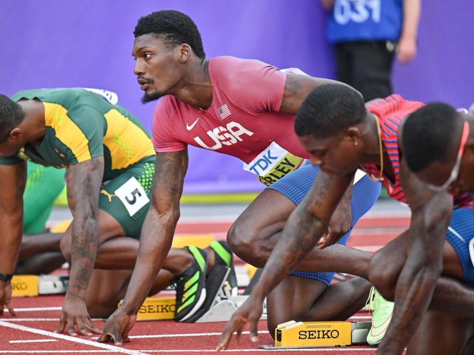 Fred Kerley looks up while surrounded by other runners on start blocks at the World Championships.