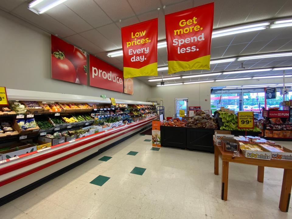The produce section with red signs hanging from ceiling at save a lot