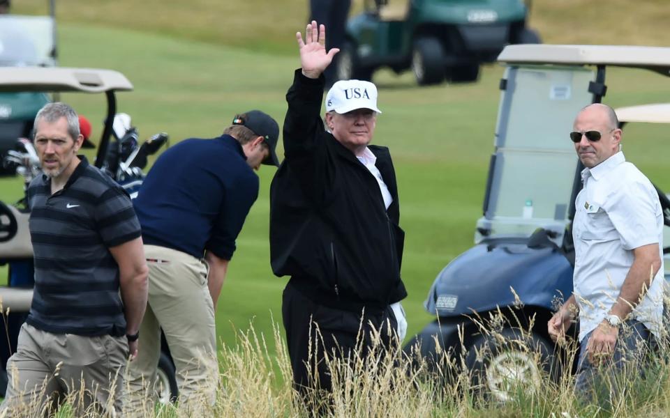 US President Donald Trump (C) gestures as he walks during a round of golf on the Ailsa course at Trump Turnberry - AFP