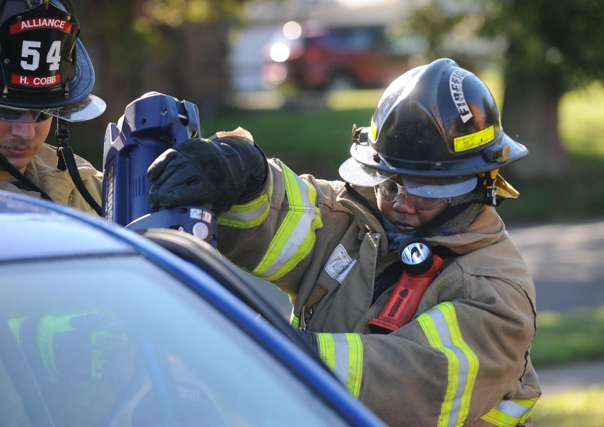 2022 Greater Alliance Carnation Festival Queen Kayla Martin is assisted by Alliance Fire Department firefighter Hunter Cobb as they use the Jaws of Life to remove a car door Friday, Aug. 12, 2022, at the main fire station in Alliance.