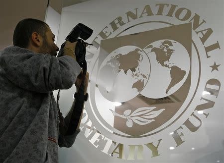 A photographer takes pictures through a glass carrying the International Monetary Fund (IMF) logo during a news conference in Bucharest March 25, 2009. REUTERS/Bogdan Cristel